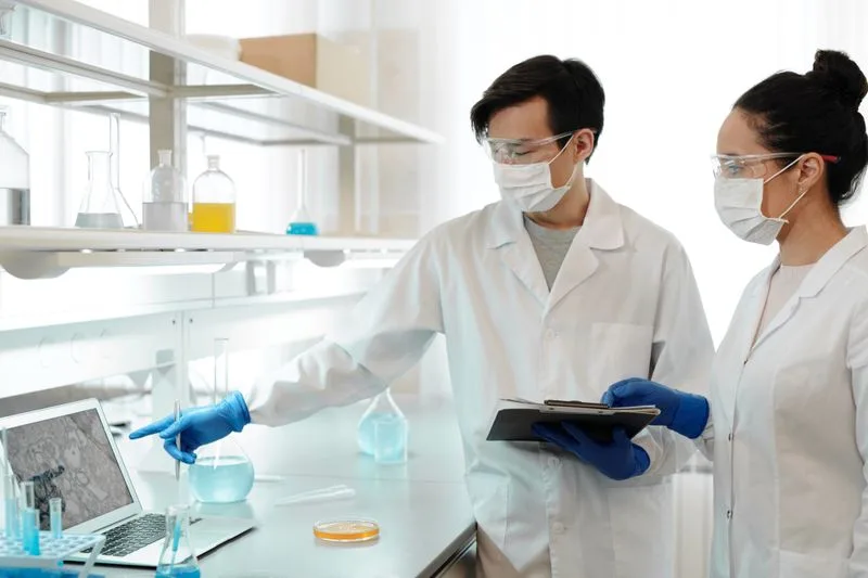 Scientists reviewing data on a laptop alongside their lab work